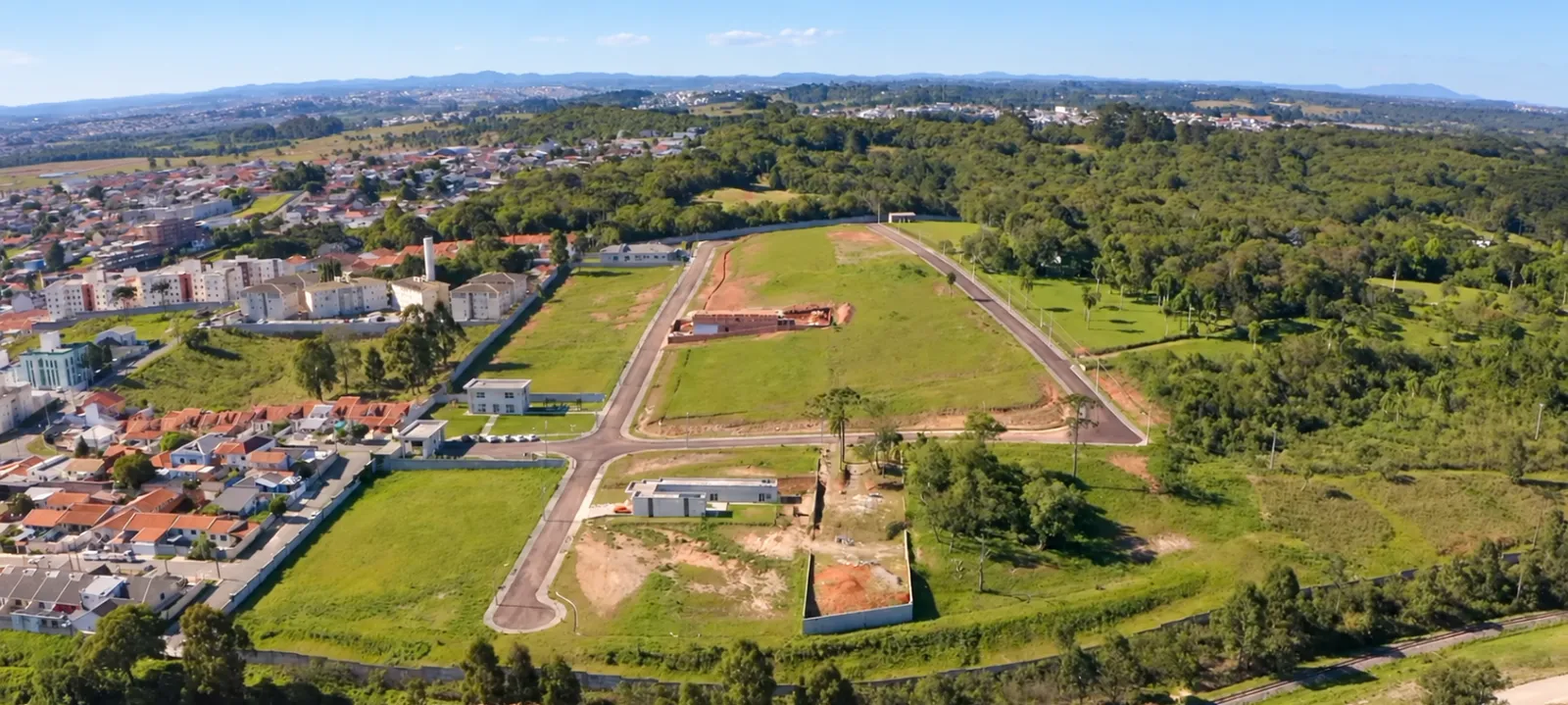 Vista aérea das ruas internas e dos lotes do Beverly Hills Residence, cercados de mata