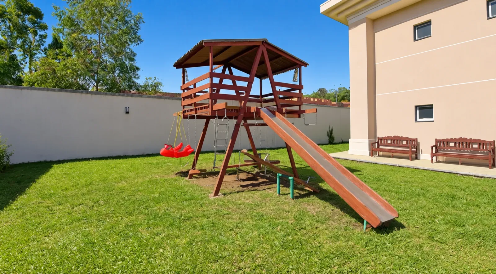 Playground de madeira com escorregador e balanços sobre o gramado